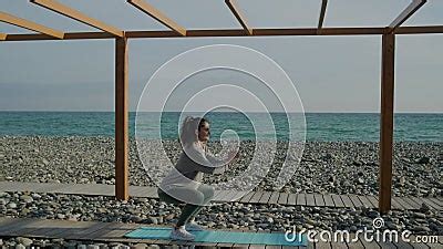 Brunette Girl Is Training Muscles Of Legs And Buttocks Squatting In Seashore Stock Footage