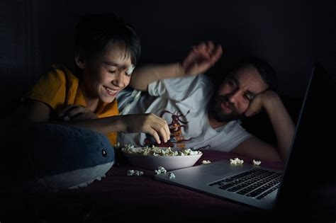 Premium Photo Father And Son Watching Movie While Eating Popcorn At Home