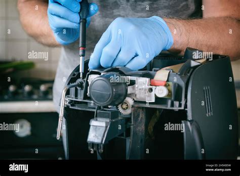 A Repairman Fixes A Broken Coffee Maker Repair Of Household Appliances