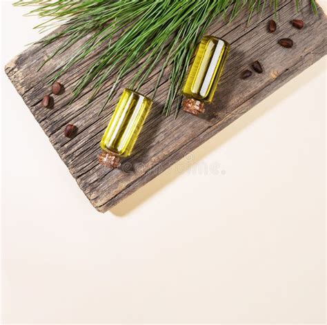 Two Small Glass Bottles Of Essential Cedar Oil On Old Wooden Board With