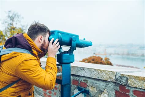 Young Man On Observation Deck Looking At Panoramic View With Binoculars