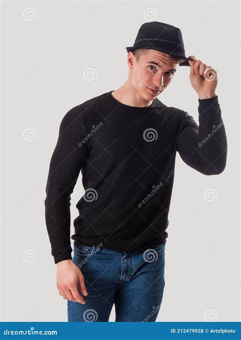 Young Man Tipping His Hat Touching Fedora Hat On His Head In Studio