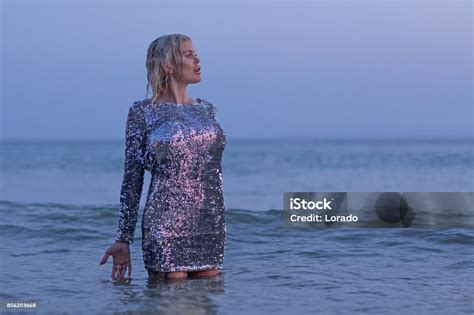 Beautiful Blonde Scandinavian Woman Standing In Sea In Silver Dress