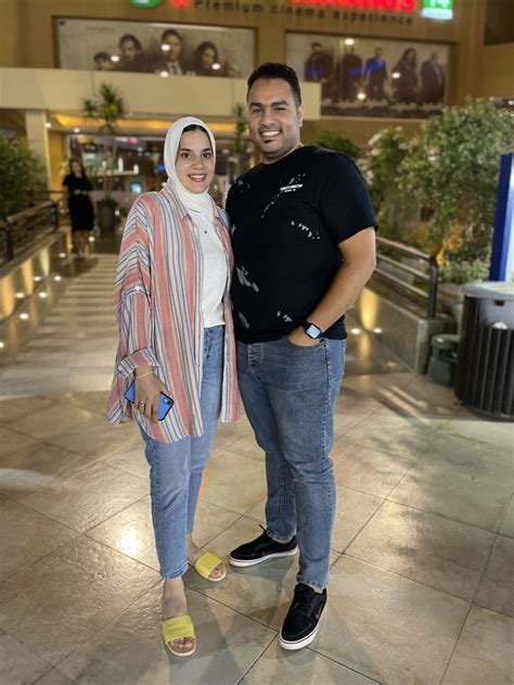 A Man And Woman Standing Next To Each Other In Front Of An Airport