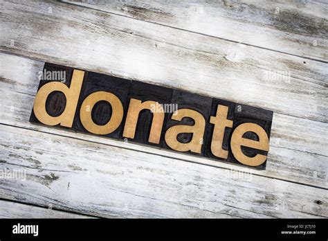 The Word Donate Written In Wooden Letterpress Type On A White Washed