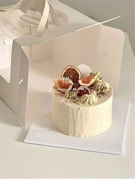 A White Cake With Fruit On Top In A Box Shaped Like An Open Gift Bag