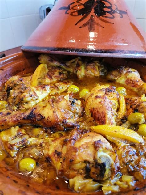 A Dish With Chicken And Olives In A Brown Pot On A Counter Top Next To