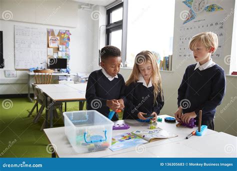 En Flicka Och Två Pojkar Som Står På En Tabell I Ett Grundskola För