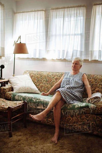 Older Woman Sitting On Sofa In Living Room Stock Photo Dissolve