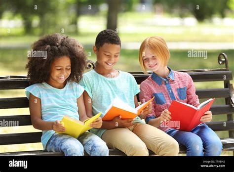 Cute Kids Reading Books On Bench Stock Photo Alamy