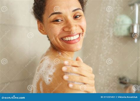 A Woman Happily Showers Smiling As She Washes Her Face Hair And Body