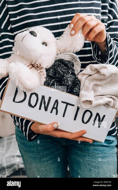 Female Volunteer Holding Donation Box With Old Used Toys And Clothes Indoors Happy Charity