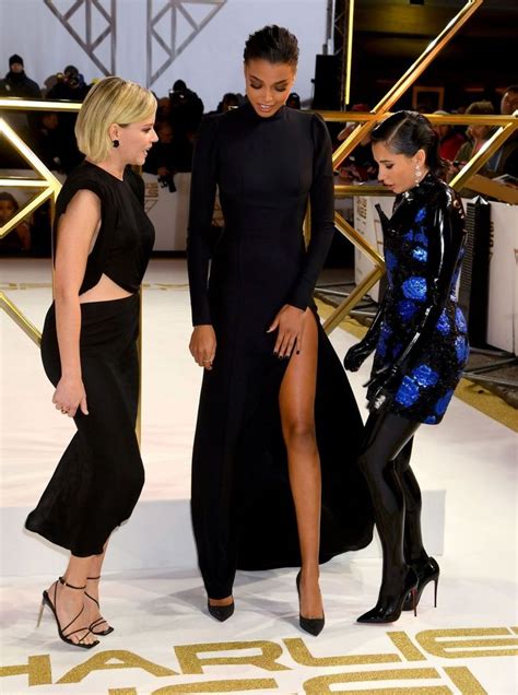 Two Women In Black Dresses Standing Next To Each Other