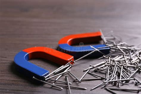 Magnets Attracting Nails on Grey Wooden Background, Closeup Stock Photo - Image of equipment ...