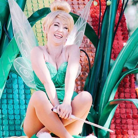 A Woman Dressed As Tinkerbell Sitting On Top Of A Fake Plant With Green