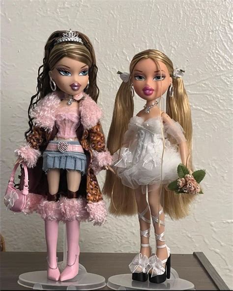 Two Dolls Standing Next To Each Other On Top Of A Table In Front Of A