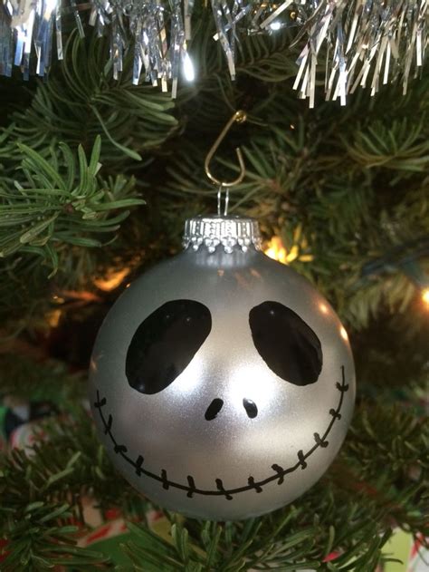 A Silver Ornament With A Jack Skellingy Face Hanging From A Christmas Tree