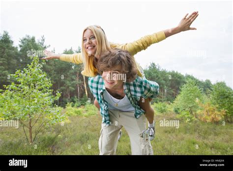 Happy Woman Enjoying Piggyback Ride On Man In Forest Stock Photo Alamy