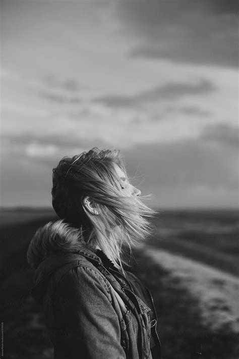 Young Woman Standing On A Hill With Hair Blowing In The Wind By