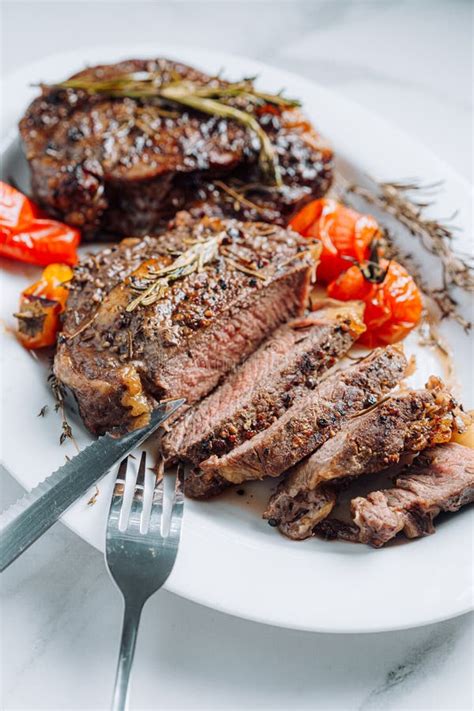 Juicy Well Fried Ribeye Steaks On A White Platter On A White Marble