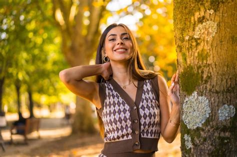 Premium Photo Brunette Model In Autumn At Sunset In A Natural City Park Next To A Tree Smiling