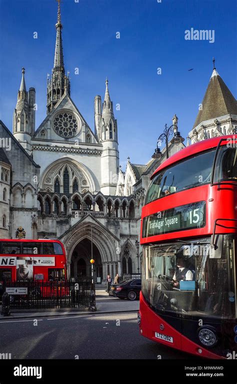 Buses Pass The Royal Courts Of Justice On The Strand In London The Building Commonly Known As