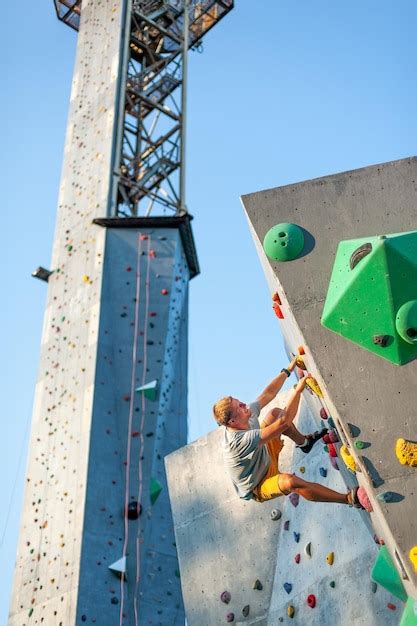 Un escalador masculino está escalando al aire libre en una roca