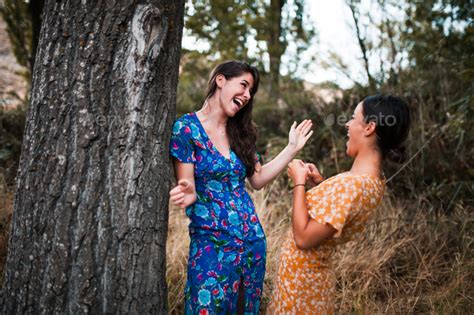 Two Young Lesbians Smiling And Caressing Each Other In The Woods Stock