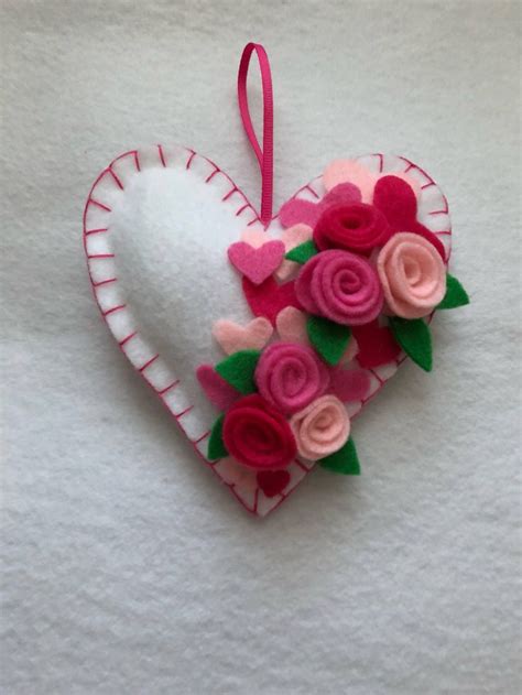 A Heart Shaped Ornament With Pink And Red Felt Flowers On It S Side