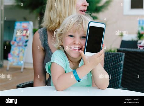 Petite Fille Blonde Assise Sur Les Genoux De Sa M Re Et De Jouer Avec Un Smartphone Photo Stock