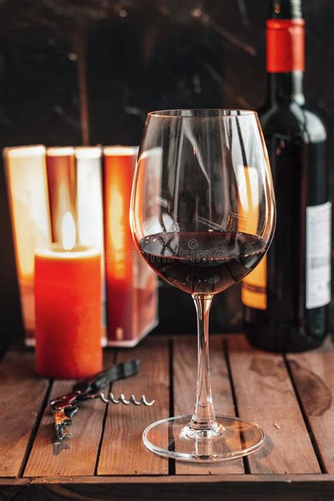 Red Wine In Glass Glass Of Red Wine Are On The Table A Candle Books And A Bottle Of Wine On