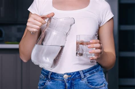 Une Jeune Femme Verse De L Eau Propre D Une Cruche Dans Un Verre La