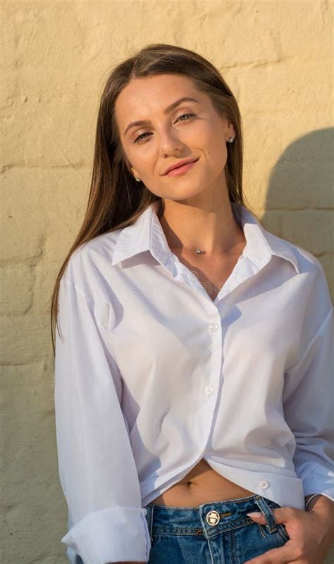 Beautiful Girl Stands At Brick Wall Background At Sunset Stock Image