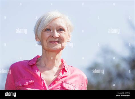 Mature Woman Smiling While Looking Away Against Sky Stock Photo Alamy