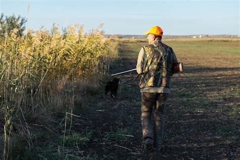 Premium Photo Mature Man Hunter With Gun While Walking On Field