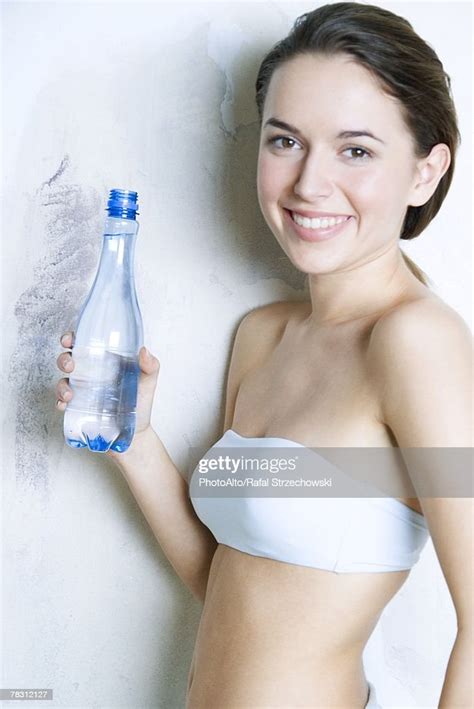 Young Woman Holding Water Bottle Smiling At Camera Dressed In Tubetop