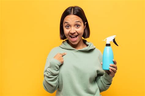 Joven latina que se siente feliz sorprendida y orgullosa señalando a