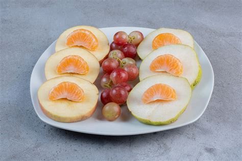 Rodajas De Manzanas Peras Mandarinas Y Uvas En Un Plato Sobre Fondo