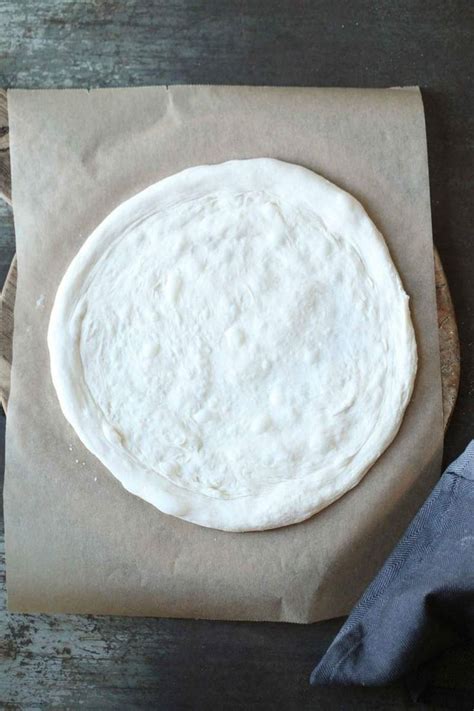 An Uncooked Pizza Sitting On Top Of A Piece Of Wax Paper Next To A Napkin