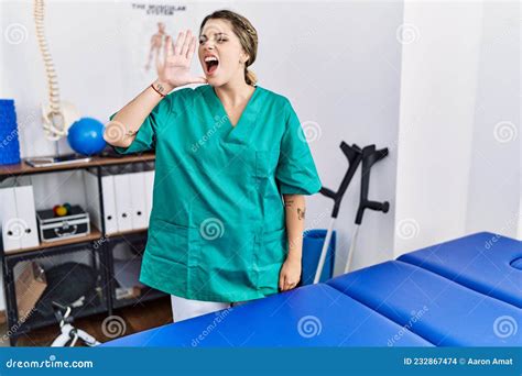 Young Hispanic Woman Wearing Physiotherapist Uniform Standing At Clinic Shouting And Screaming