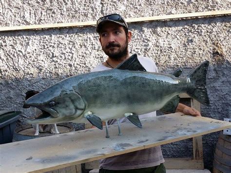 A Man Holding A Large Fish On Top Of A Wooden Table