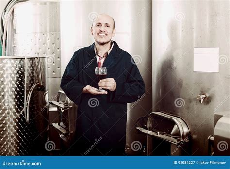 Cheerful Mature Man Winery Worker Looking At Glass Of Red Wine Stock