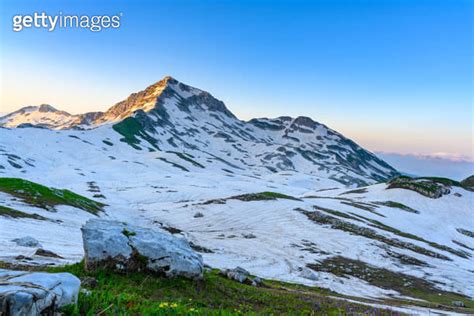 The Snowdrifts And Green Grass On Top Of Mountains In The Tropical