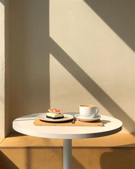 A White Table Topped With A Plate Of Food And A Cup Of Coffee Next To It