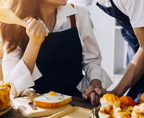 Um jovem casal adulto feliz fazendo o café da manhã e bebendo café