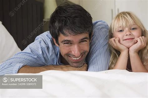 Father And Daughter Lying On A Bed Superstock