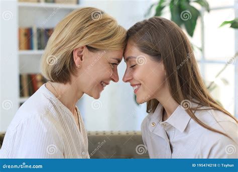 Happy Middle Aged Mother And Daughter Talking On Sofa In Living Room