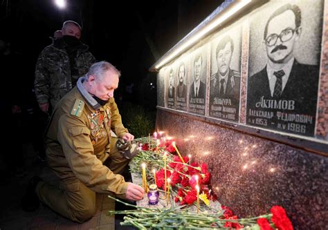 A man lights a candle at a memorial, dedicated to firefighters and ...