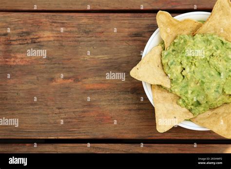 Delicious Guacamole Made Of Avocados With Nachos On Wooden Table Top