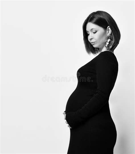 Pregnant Woman In Black Tight Dress And Massive Earrings She Put Hand On Her Belly Posing